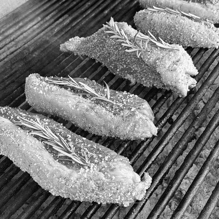 Cortes de carne con romero sobre las brasas de la parrilla